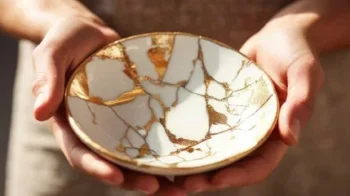Bol en porcelaine réparé avec de l’or selon la technique du Kintsugi, tenu dans deux mains